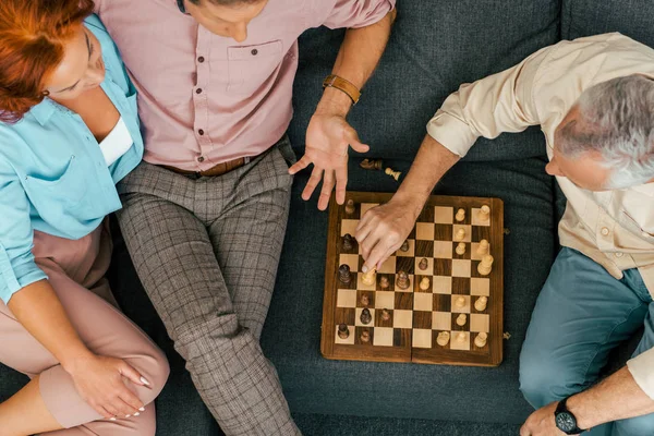 Recortado tiro de viejos amigos jugando ajedrez juntos en casa - foto de stock