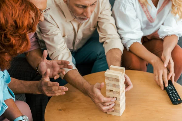 Recortado disparo de amigos maduros pasar tiempo juntos y jugar con bloques de madera en casa - foto de stock