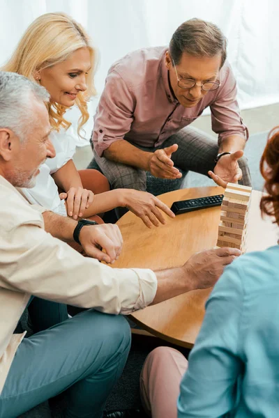 High angle view of mature friends playing with wooden blocks on table at home — Stock Photo