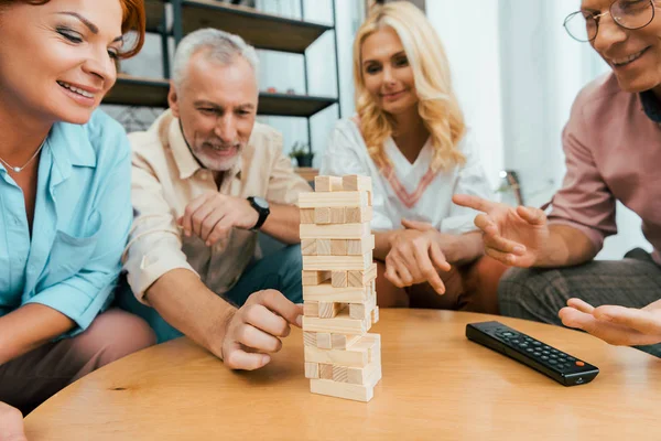 Sorridenti amici maturi che si riuniscono e giocano con blocchi di legno sul tavolo — Foto stock
