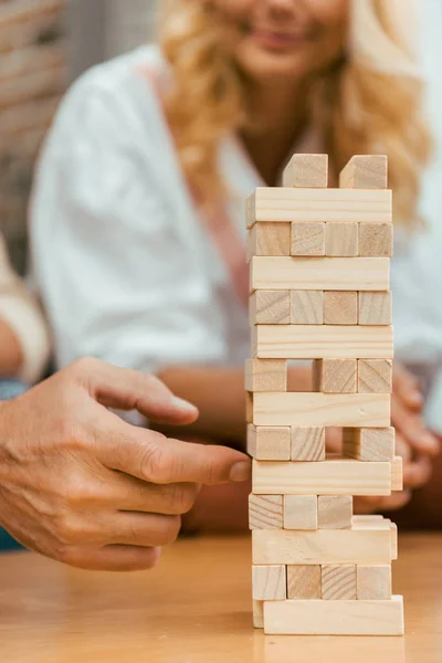 Abgeschnittene Aufnahme von reifen Menschen, die zu Hause mit Holzklötzen auf dem Tisch spielen — Stockfoto