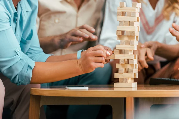 Schnappschuss reifer Freunde beim Turmbau aus Holzklötzen auf dem Tisch — Stockfoto