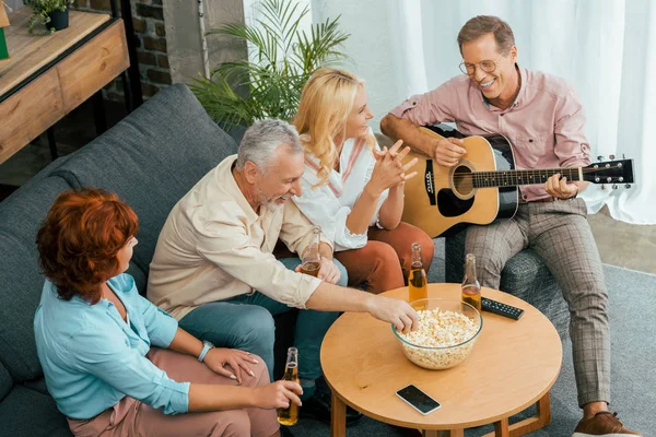 Blick aus der Vogelperspektive auf glückliche alte Freunde, die zu Hause Zeit mit Gitarre und Bier verbringen — Stockfoto