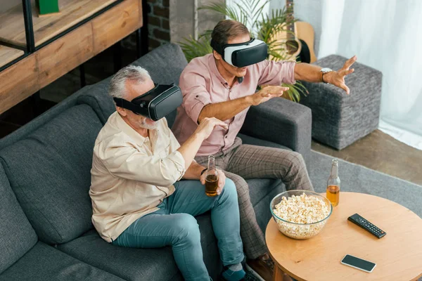 Ansicht reifer männlicher Freunde, die Bier trinken und Virtual-Reality-Headsets verwenden — Stockfoto
