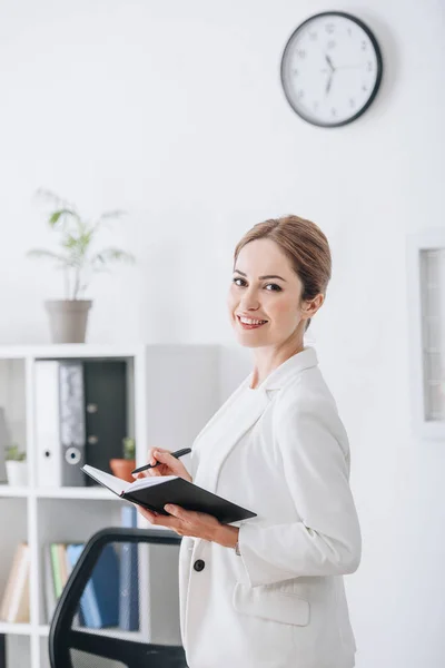 Attraente donna d'affari sorridente che lavora con pianificatore in ufficio moderno — Foto stock