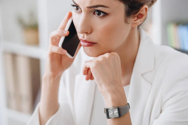 Attractive worried businesswoman talking on smartphone in office — Stock Photo