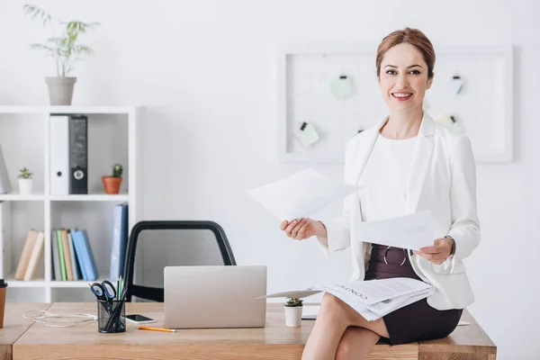 Executive businesswoman doing paperwork while sitting on table with laptop — Stock Photo