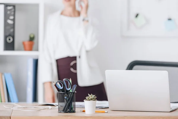 Selektive Fokussierung des Arbeitsplatzes mit Laptop und Geschäftsfrau im Büro — Stockfoto