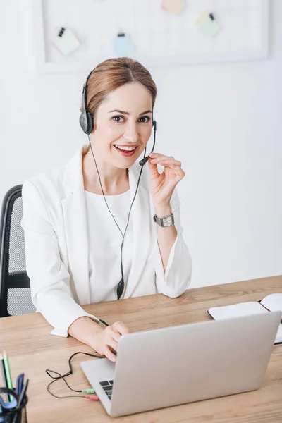 Operador femenino profesional que trabaja con auriculares y portátil en el espacio de trabajo - foto de stock