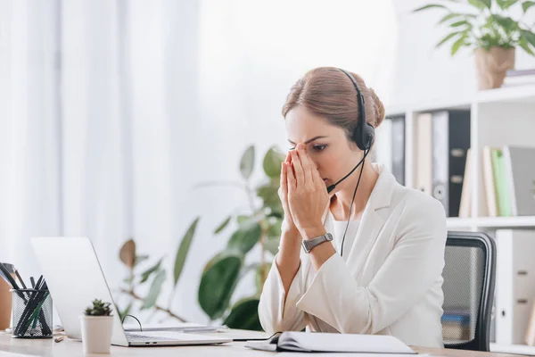 Opérateur féminin effrayé travaillant avec casque et ordinateur portable dans le centre d'appel — Photo de stock