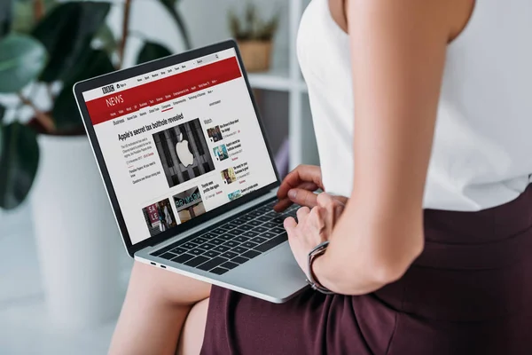 Vista recortada de la mujer de negocios utilizando el ordenador portátil con el sitio web de noticias bbc - foto de stock