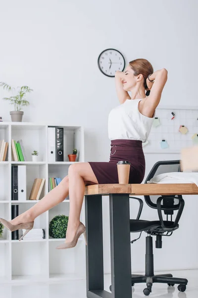 Feliz mujer de negocios que se estira y se relaja durante el descanso de café en la oficina moderna - foto de stock