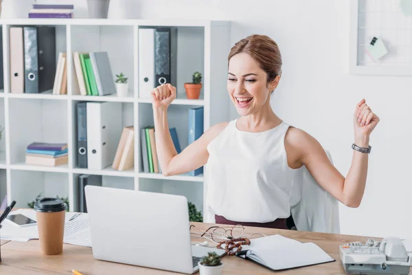 Femme d'affaires réussie célébrant sur le lieu de travail et regardant ordinateur portable — Photo de stock