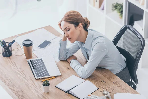 Blick aus der Vogelperspektive auf erschöpfte erwachsene Geschäftsfrau, die am Arbeitsplatz im modernen Büro schläft — Stock Photo