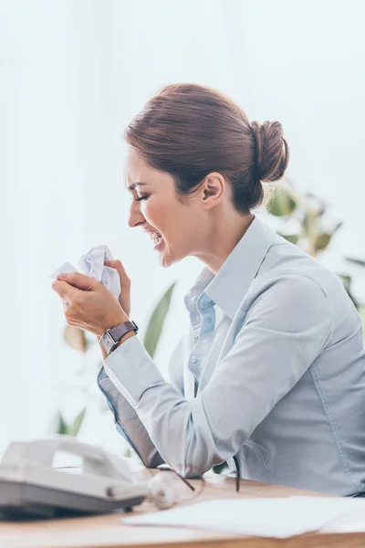 Side view of stressed adult businesswoman crumpling paper at workplace — Stock Photo