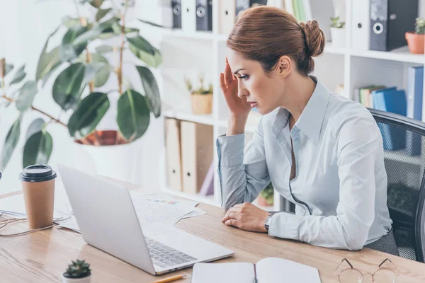 Overworked adult businesswoman with headache sitting at workplace — Stock Photo