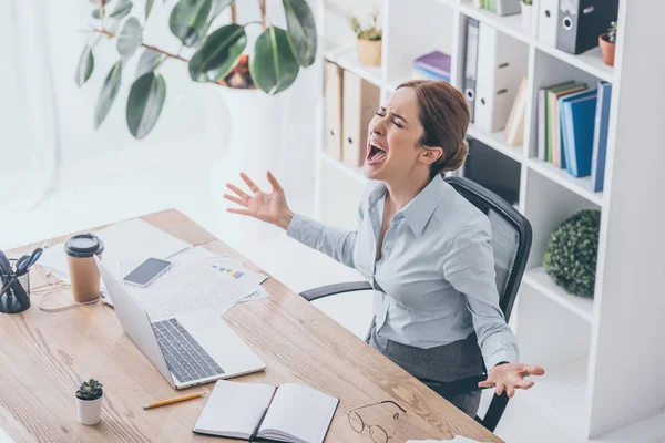 Vista de ángulo alto de la mujer de negocios estresada gritando en el lugar de trabajo - foto de stock