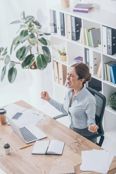 Vista de ángulo alto de la mujer de negocios adulta estresada gritando en el lugar de trabajo - foto de stock