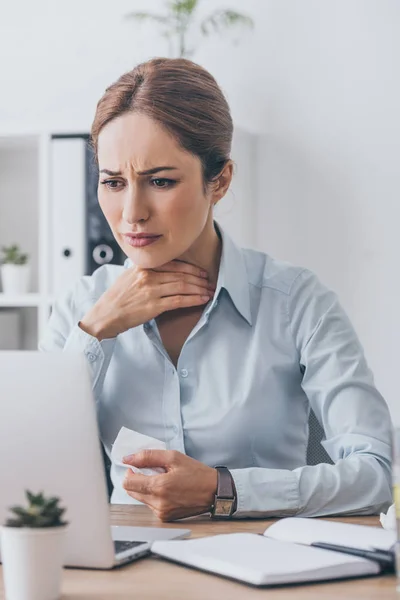 Страдает больная деловая женщина с больным горлом пытается работать в офисе — стоковое фото