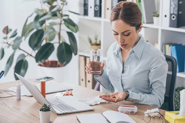 Adult sick businesswoman taking pills at modern workplace — Stock Photo