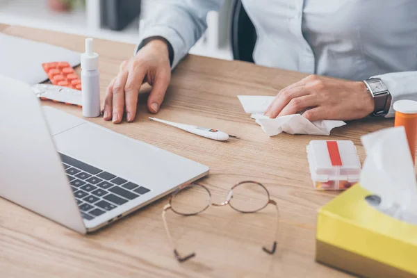 Plan recadré de femme d'affaires avec des médicaments et un thermomètre électrique assis sur le lieu de travail — Photo de stock