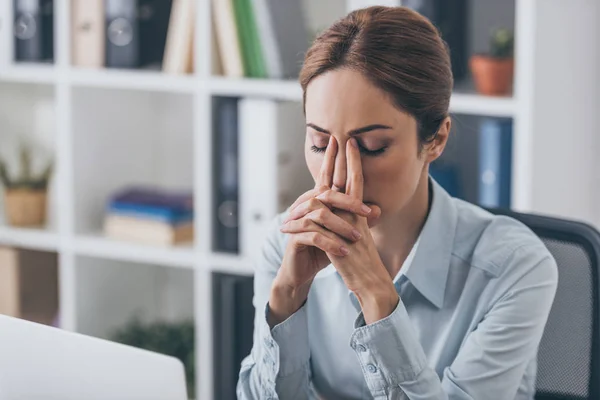 Depressed adult businesswoman sitting with closed eyes at office — Stock Photo