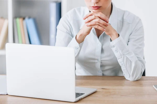 Обрезанный снимок деловой женщины, сидящей на рабочем месте с ноутбуком — стоковое фото