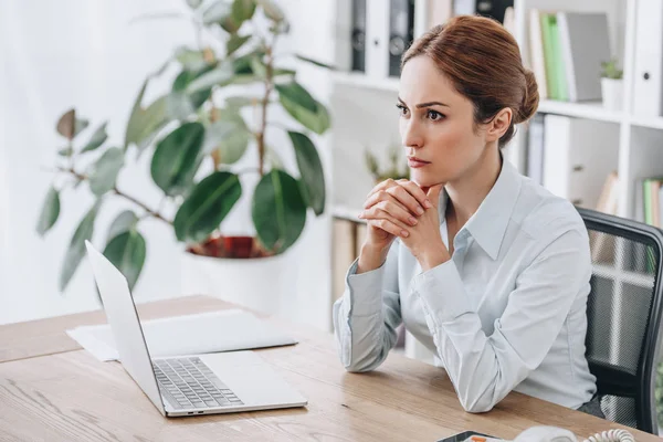 Ritratto ravvicinato di una seria donna d'affari seduta sul posto di lavoro e che guarda dall'alto verso l'ufficio — Foto stock