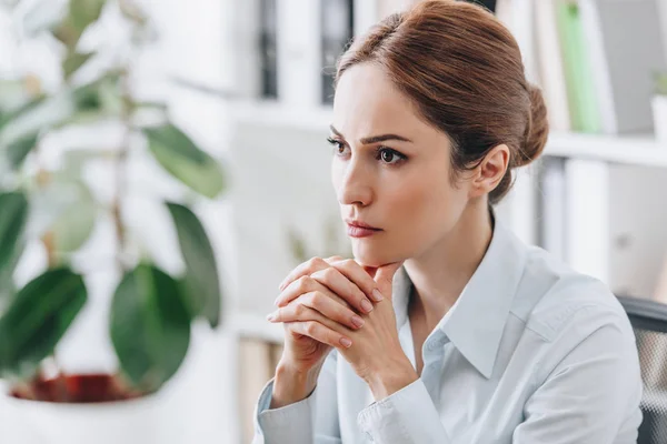 Close-up portrait of serious businesswoman sitting at workplace and looking away — Stock Photo