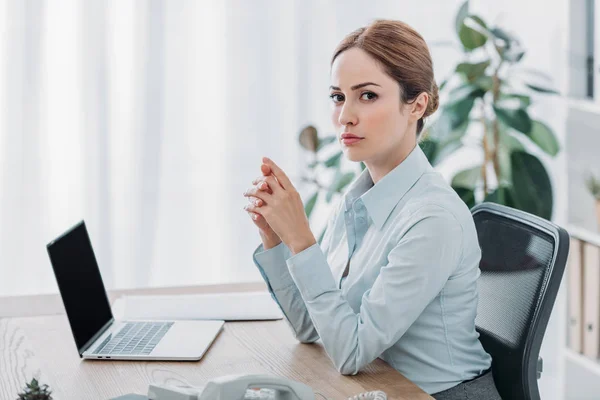 Erfolgreiche erwachsene Geschäftsfrau sitzt am Arbeitsplatz im Büro und blickt in die Kamera — Stockfoto
