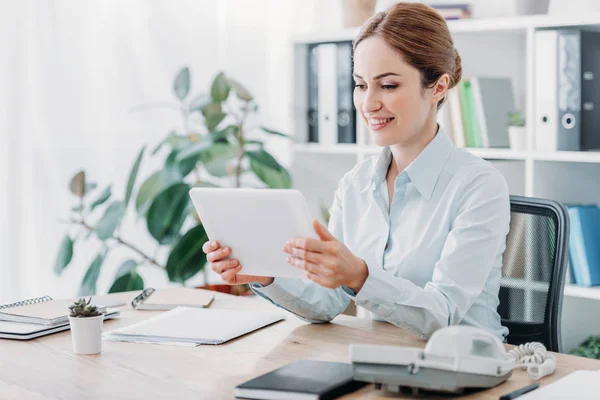 Lächelnde schöne Geschäftsfrau, die im Büro mit Tablet arbeitet — Stockfoto