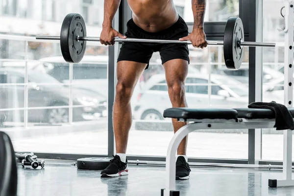 Cropped shot of young athletic man lifting barbell in gym — Stock Photo