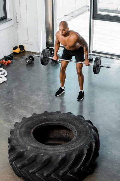 Високий кут зору на спортивний голий афроамериканський спортсмен, що піднімає штангу в спортзалі — стокове фото