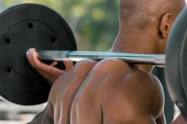 Cropped shot of muscular african american sportsman lifting barbell in gym — Stock Photo