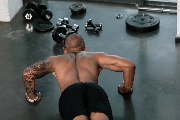 Hochwinkelaufnahme eines hemdlosen jungen Mannes, der Liegestütze im Fitnessstudio macht — Stockfoto