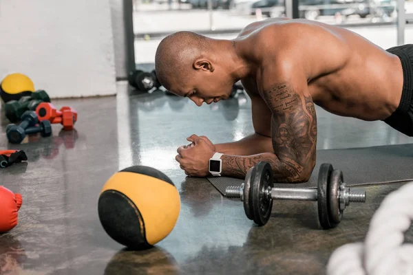 Visão lateral do homem americano africano muscular fazendo flexões no ginásio — Fotografia de Stock