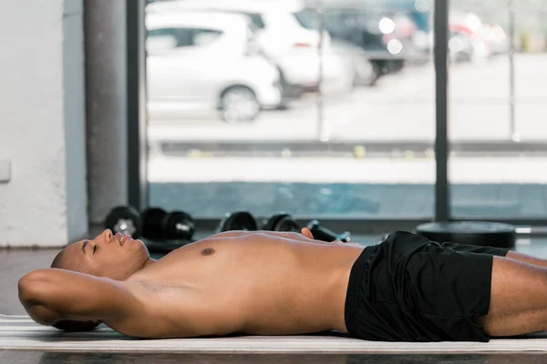 Selective focus of african american sportsman resting on fitness at at gym — Stock Photo