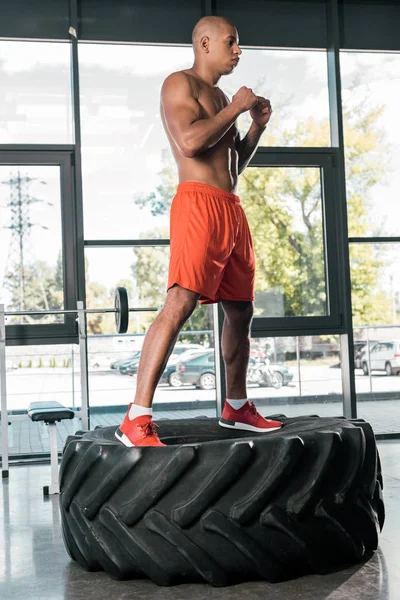 Handsome african american athlete doing exercise on tire at gym — Stock Photo