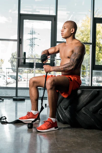 Vista lateral del deportista afroamericano envolviendo la mano en venda de boxeo en el gimnasio - foto de stock