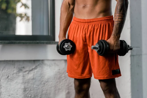 Imagem cortada de tatuado Africano americano desportista exercitando com halteres no ginásio — Fotografia de Stock