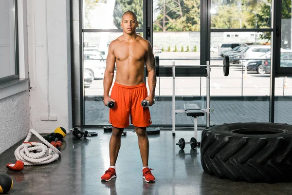 Young african american sportsman exercising with dumbbells at gym — Stock Photo