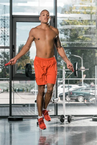 Atleta afroamericano sin camisa haciendo ejercicio con cuerda de salto en el gimnasio - foto de stock