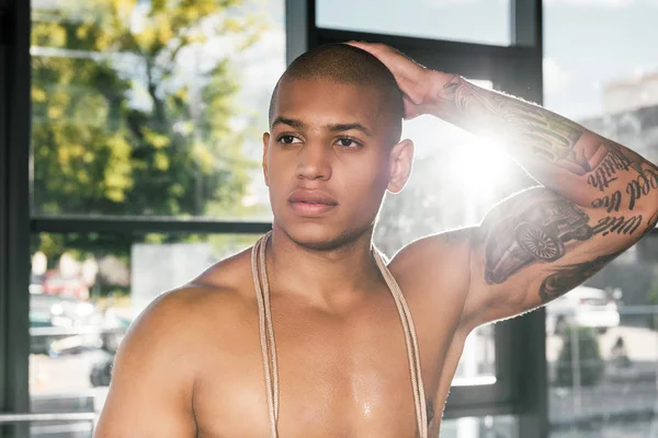 Retrato de deportista afroamericano musculoso con mano tatuada en el gimnasio - foto de stock