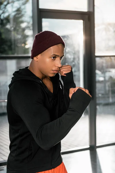 Вид сбоку на молодого африканского боксера, тренирующегося в спортзале — стоковое фото