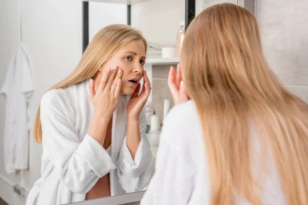 Erwachsene schwangere Frau mit Hautproblemen sieht ihr Gesicht im Badezimmer durch den Spiegel an — Stockfoto