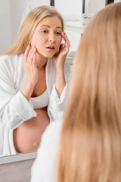 Schwangere mit Hautproblemen blickt im Badezimmer durch Spiegel auf ihr Gesicht — Stockfoto