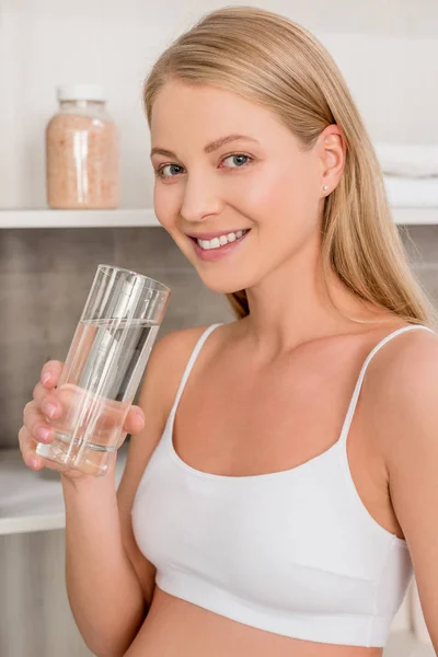 Close-up portrait of pregnant woman with glass of water looking at camera in bathroom — Stock Photo