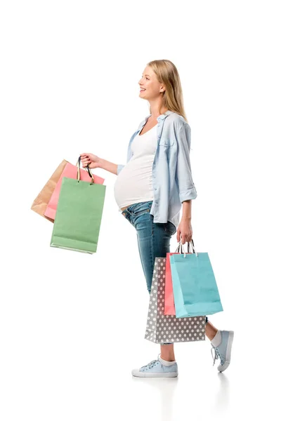 Alegre madre embarazada sosteniendo bolsas aisladas en blanco - foto de stock