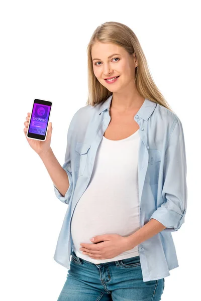 Hermosa mujer embarazada rubia mostrando teléfono inteligente con aplicación de compras aislado en blanco - foto de stock
