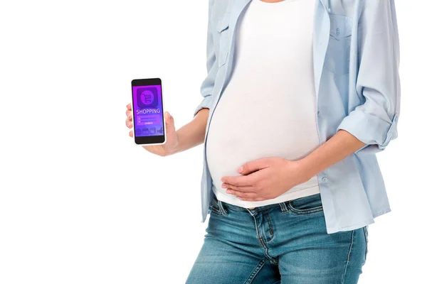 Ausgeschnittene Ansicht einer schwangeren Frau, die ein Smartphone mit einem auf Weiß isolierten Einkaufsgerät präsentiert — Stockfoto